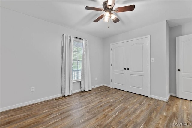 unfurnished bedroom with a ceiling fan, baseboards, visible vents, and wood finished floors