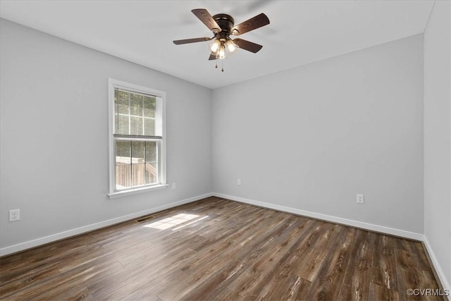 empty room featuring baseboards, ceiling fan, dark wood finished floors, and visible vents