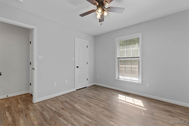 spare room featuring baseboards, ceiling fan, wood finished floors, and visible vents