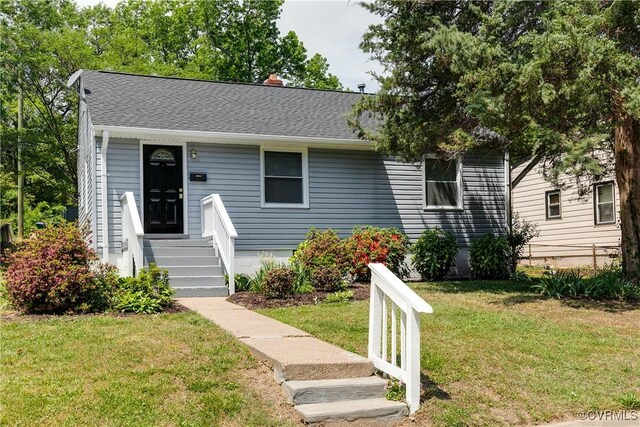 view of front of house featuring a shingled roof, a chimney, and a front yard