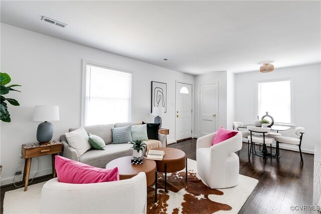 living room featuring baseboards, visible vents, and wood finished floors