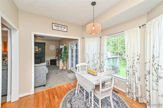 dining space with baseboards, light wood-style flooring, a fireplace, and french doors