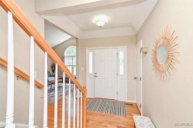 entryway featuring stairs, baseboards, vaulted ceiling, and light wood-style flooring