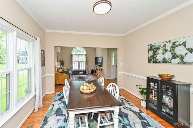 dining room featuring baseboards, ornamental molding, and light wood-style flooring