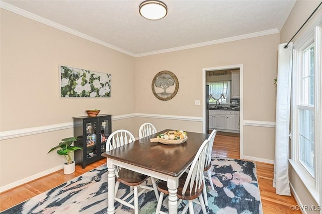 dining room with crown molding, baseboards, and light wood finished floors