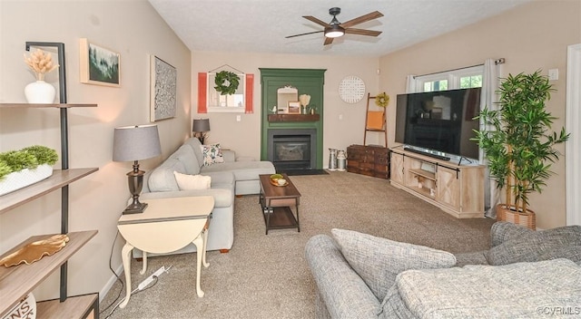 carpeted living room featuring a fireplace with flush hearth and ceiling fan