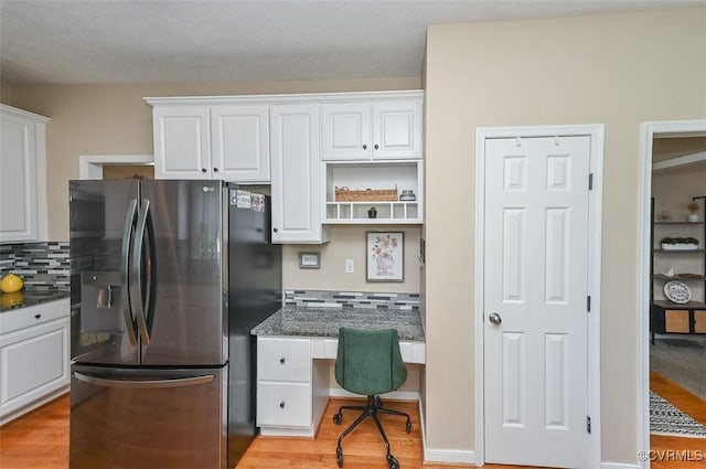 kitchen featuring stainless steel fridge, decorative backsplash, light wood-style floors, and white cabinetry