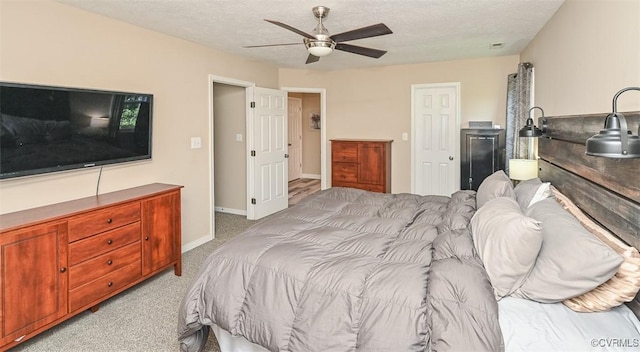 bedroom featuring baseboards, ceiling fan, light carpet, and a textured ceiling