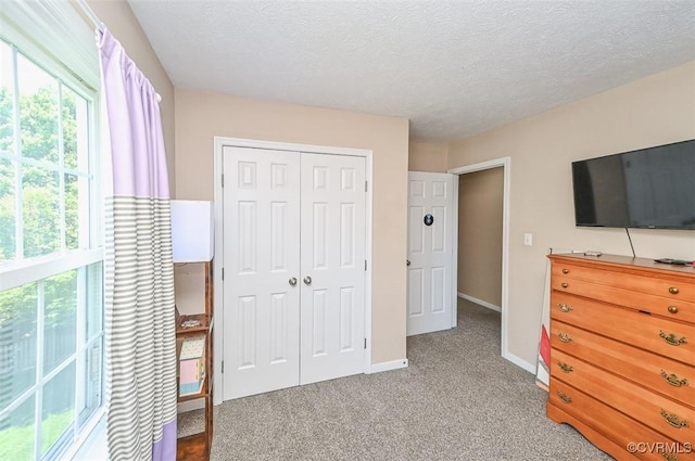 bedroom with a closet, a textured ceiling, carpet, and baseboards