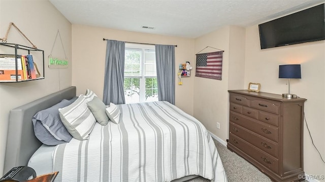 carpeted bedroom featuring a textured ceiling, visible vents, and baseboards
