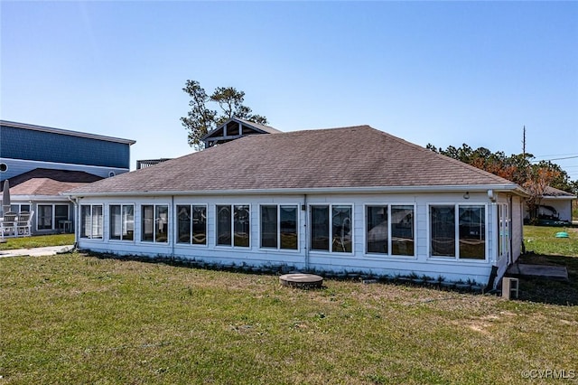back of property with a lawn and a shingled roof