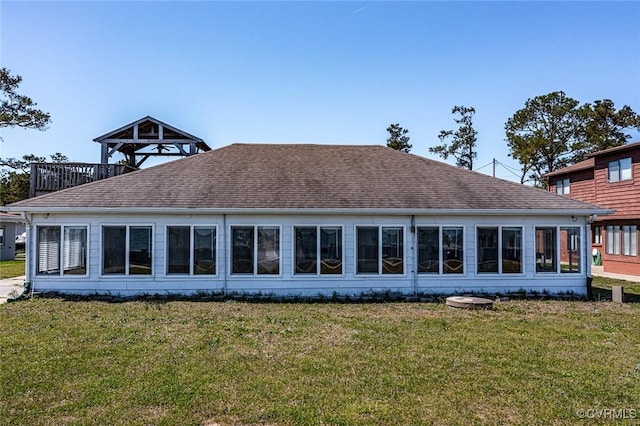 rear view of house with a yard and a shingled roof