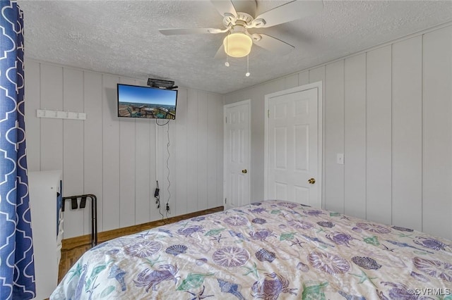 bedroom featuring a decorative wall, a ceiling fan, and a textured ceiling