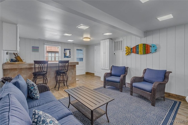 living room featuring light wood-style flooring and a bar