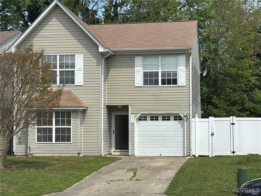 traditional home featuring a gate, fence, a front yard, and a garage