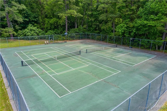 view of sport court featuring a view of trees, community basketball court, and fence