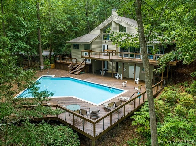 community pool with stairway, a patio, and a deck