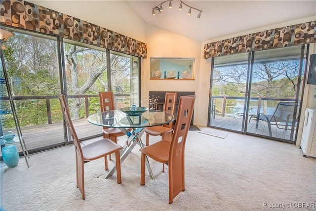 carpeted dining area featuring vaulted ceiling
