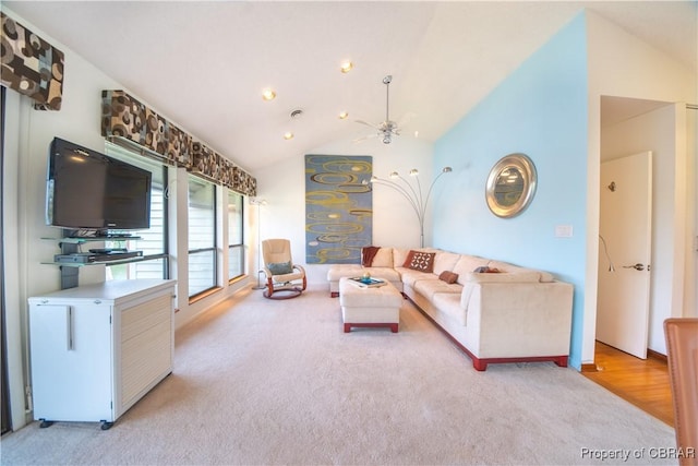 living room featuring vaulted ceiling, a ceiling fan, and light colored carpet
