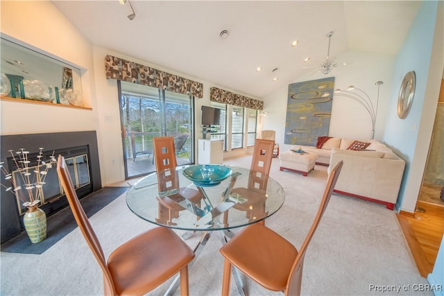dining room with a fireplace with flush hearth, vaulted ceiling, and baseboards