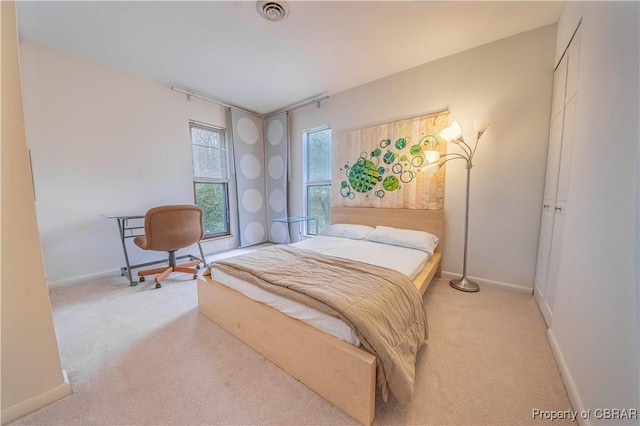 bedroom featuring baseboards, visible vents, and light colored carpet