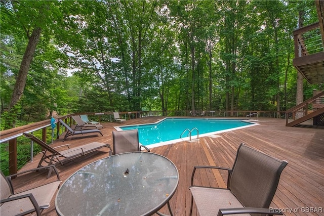 view of pool with a wooden deck, stairs, outdoor dining space, and a fenced in pool