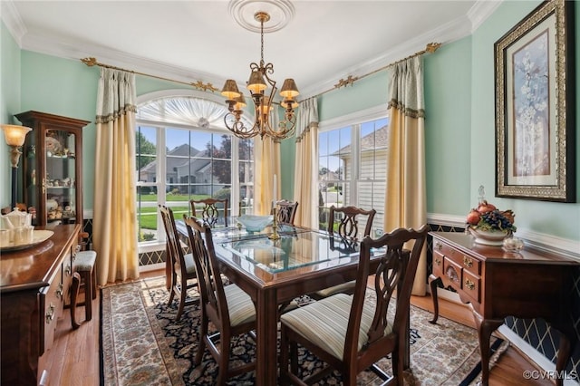 dining area featuring an inviting chandelier, ornamental molding, wood finished floors, and plenty of natural light
