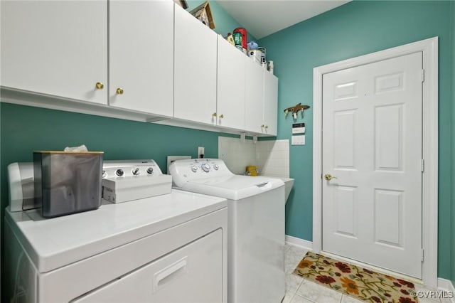 washroom with washing machine and dryer, baseboards, cabinet space, and light tile patterned floors
