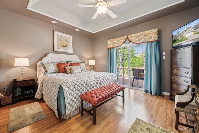 bedroom featuring baseboards, wood finished floors, a raised ceiling, and access to exterior