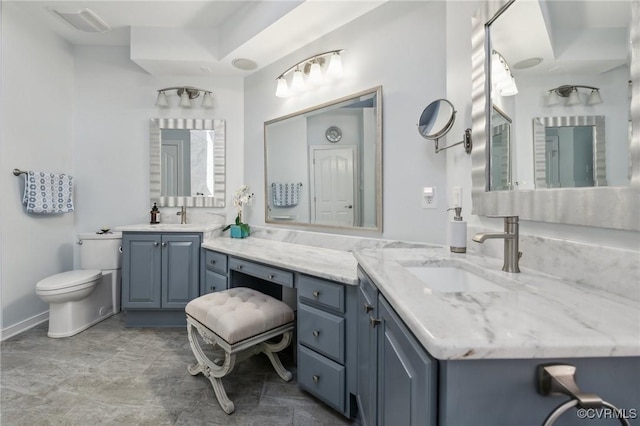 bathroom with two vanities, toilet, and a sink