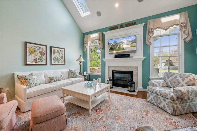 living room with a skylight, a wealth of natural light, wood finished floors, and high vaulted ceiling
