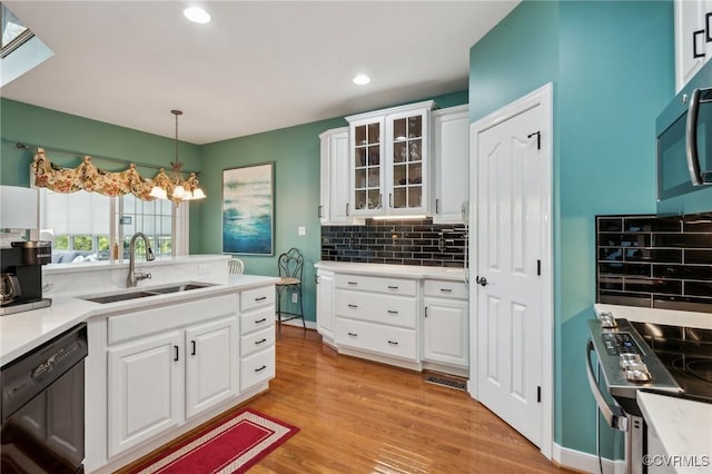 kitchen with light wood finished floors, stainless steel appliances, backsplash, light countertops, and a sink