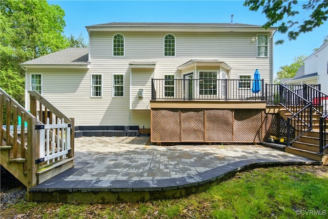 rear view of property with stairs, a wooden deck, and a patio