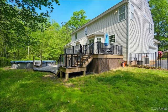 back of property featuring a yard, a deck, an attached garage, and a covered pool