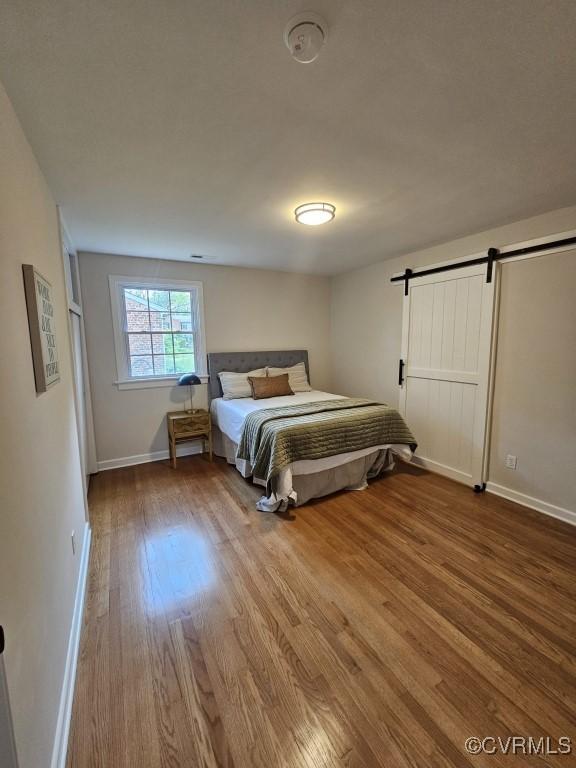 3109 Comet Rd, Richmond, VA 23294 - bedroom with a barn door, baseboards, and wood finished floors