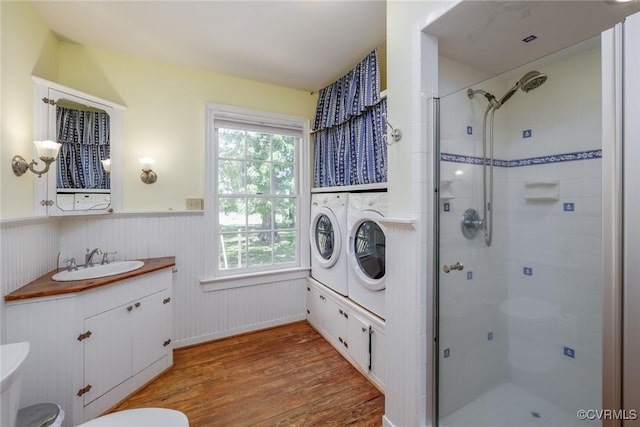 full bath featuring wainscoting, vanity, a shower stall, wood finished floors, and washer and clothes dryer
