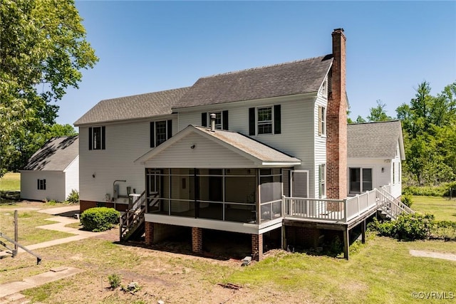 rear view of house with a chimney, roof with shingles, a lawn, a wooden deck, and a sunroom