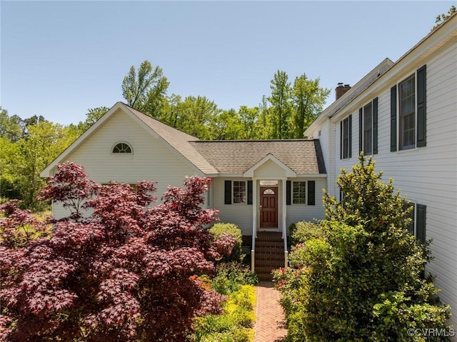 view of front of home featuring a chimney and a shingled roof