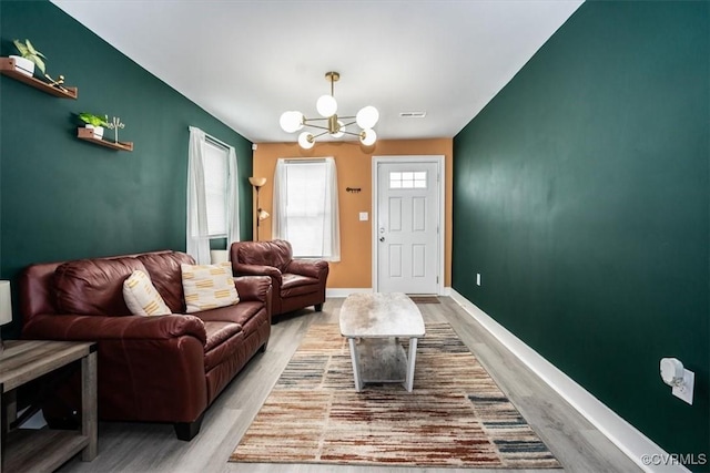 living area with baseboards, visible vents, light wood finished floors, and a chandelier