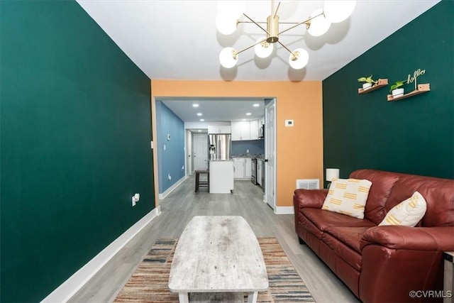 living room featuring visible vents, baseboards, a notable chandelier, and light wood-type flooring