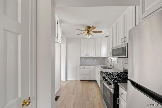 3605 Pemberton Ave, Henrico, VA 23222 - kitchen with stainless steel appliances, a sink, a ceiling fan, light wood-style flooring, and white cabinets