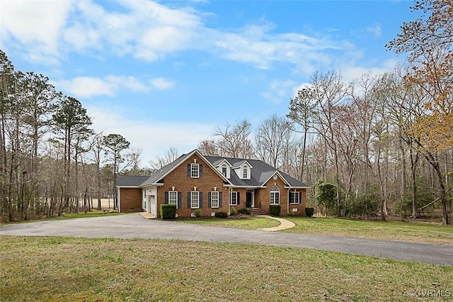 view of front of home with brick siding, a front lawn, and driveway