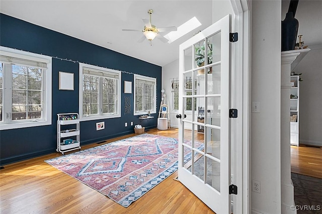 interior space with wood finished floors, ceiling fan, french doors, and a skylight