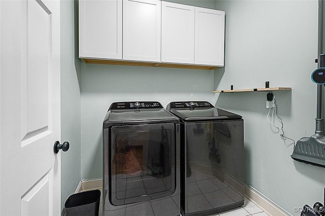 laundry area with baseboards, light tile patterned floors, cabinet space, and washing machine and dryer