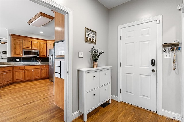 interior space with light wood-style flooring, brown cabinets, appliances with stainless steel finishes, and baseboards