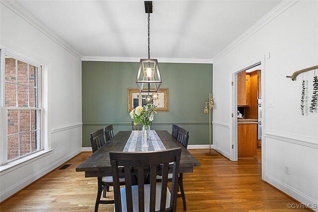 dining space with ornamental molding, a healthy amount of sunlight, and wood finished floors