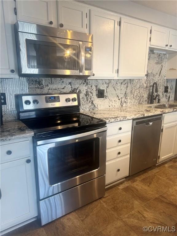 kitchen featuring decorative backsplash, white cabinetry, stainless steel appliances, and a sink