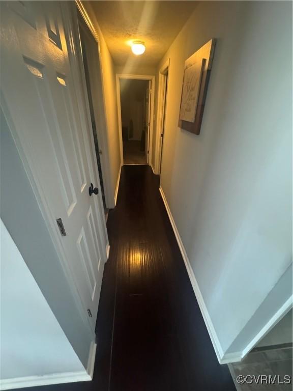 corridor with baseboards and dark wood-style flooring