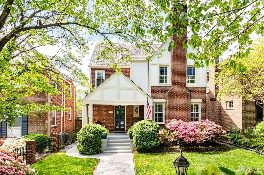 4103 Kensington Ave, Richmond, VA 23221 - tudor house with brick siding, french doors, a chimney, and a front lawn