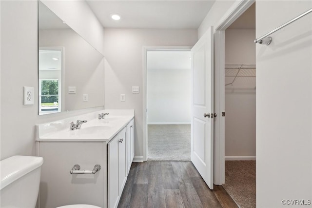 full bath featuring wood finished floors, a sink, double vanity, and toilet